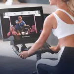 Donna che si allena su una cyclette e visualizza una lezione iFIT su un display NordicTrack