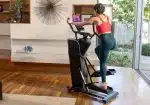 Donna in pantaloncini e maglietta rossa si allena su Ellittica con Volano Anteriore Bowflex Max Trainer SEi