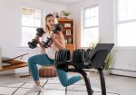 Donna in affondo con manubri regolabili, BowFlex SelectTech Stand con tablet sullo sfondo