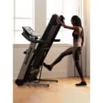 Donna ripiega il Tapis Roulant NordicTrack Elite 1000 per riporlo comodamente