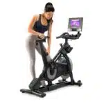 Donna che regola la sella e il manubrio della Spin Bike NordicTrack S10i