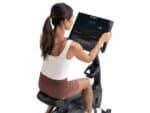 Donna da dietro si allena su Cyclette Verticale con display acceso