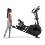 Donna sposta un'Ellittica AirGlide LE Nordictrack con volano anteriore piegata per il trasporto