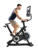 Uomo che pedala sulla NordicTrack S27i con monitor verticale | Allenamento indoor dinamico