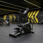 Ellittica BodyJoy CT21PRO in piedi su pavimento nero di una palestra moderna con luci al neon